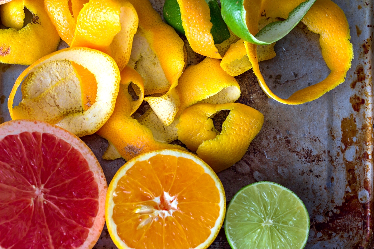 Orange, lime and grapefruit halves with orange and green peels around them.