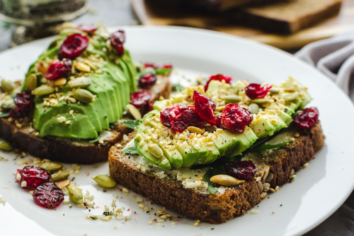 Toasts with mashed avocado, dried cranberries and seeds sprinkled over.