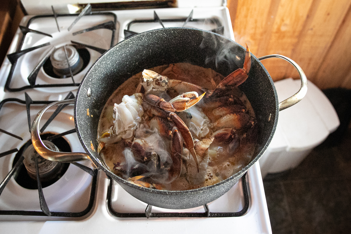 Dark brown and orange Dungeness crab pieces have been added to the pot.