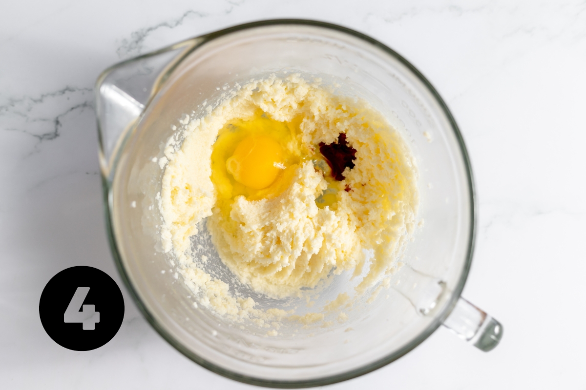 Creamed butter and sugar in a large glass measuring cup with an egg and some vanilla added but not yet mixed in.