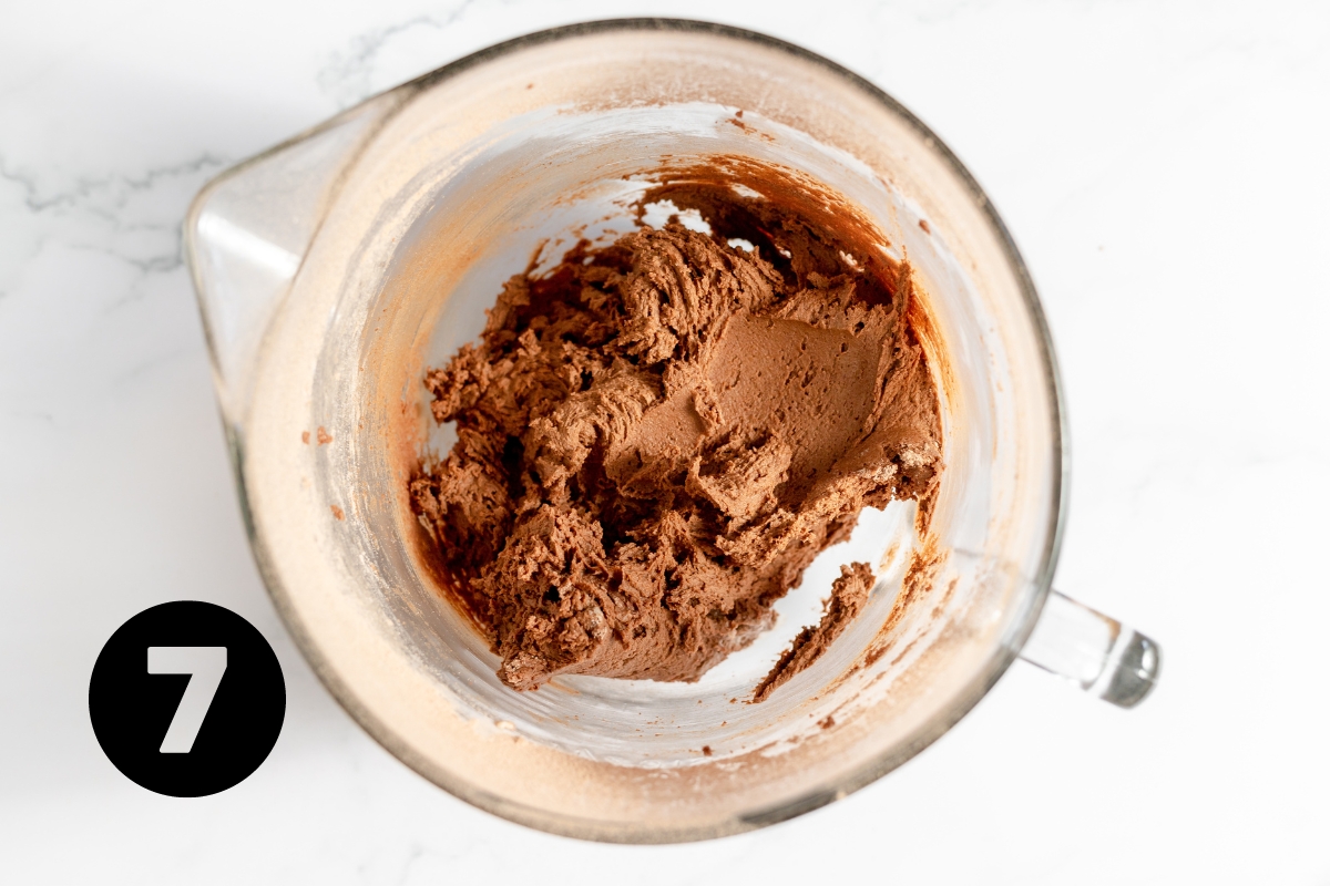 Dark brown thick cookie dough in measuring cup.