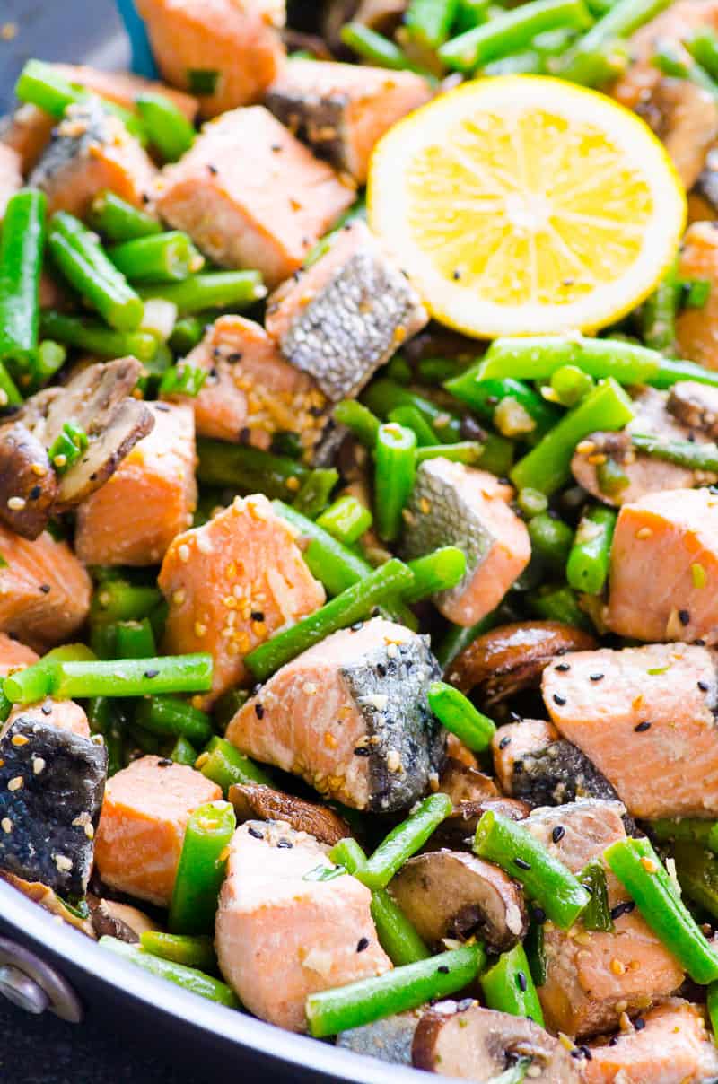 Closeup of salmon stir-fry with pink cubes of salmon and green beans.