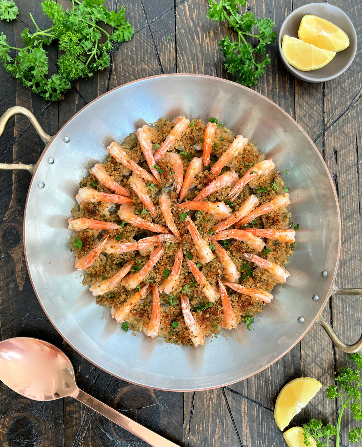 A large round silver paella pan with shrimp in a circle in the middle.