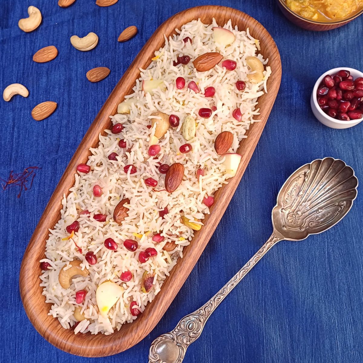 Red studded white rice in an oblong wooden bowl on a blue tablecloth.