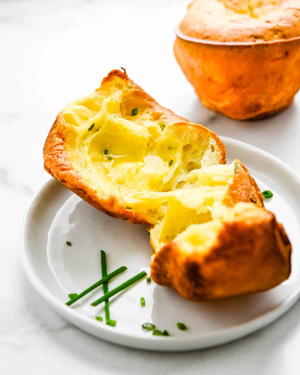 A popover ripped in half to reveal the bright yellow, airy interior.