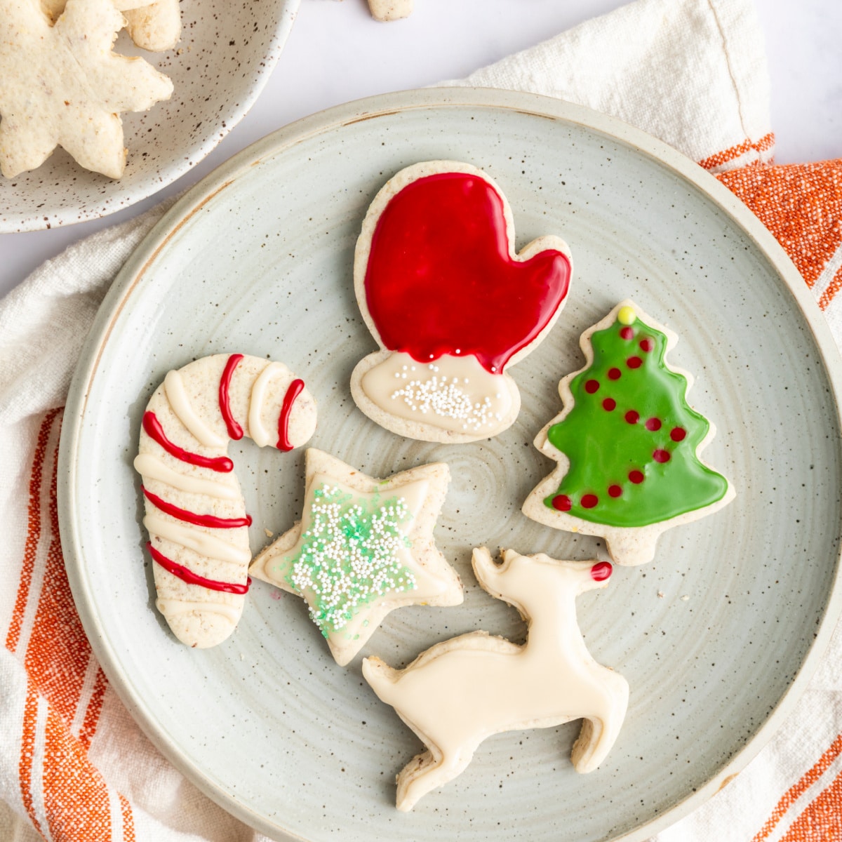 5 cookies in the shape of a mitten, a candy cane, a star, a reindeer and a tree with icing.