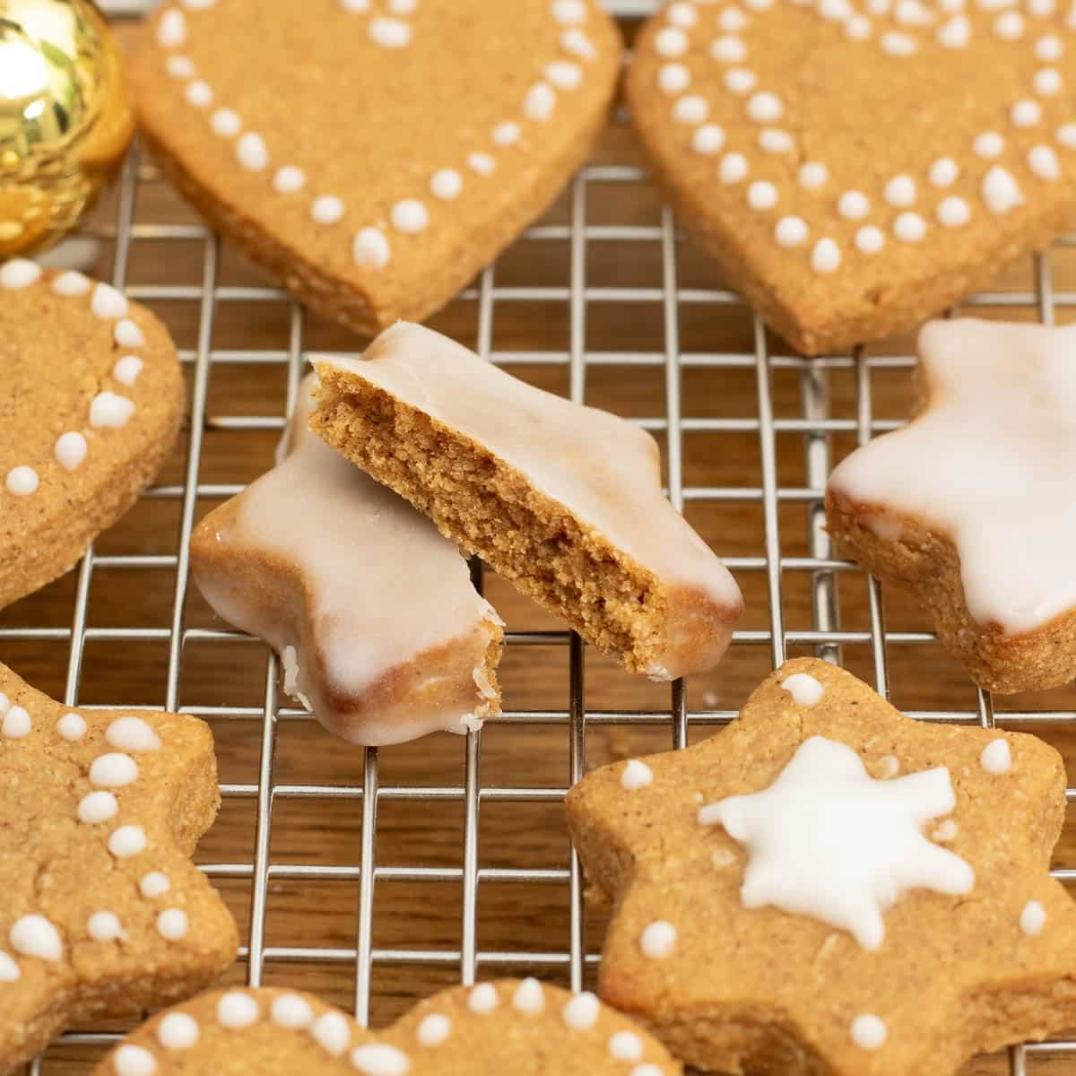 Light brown heart and star shaped cookies with white icing dots on a wire rack.