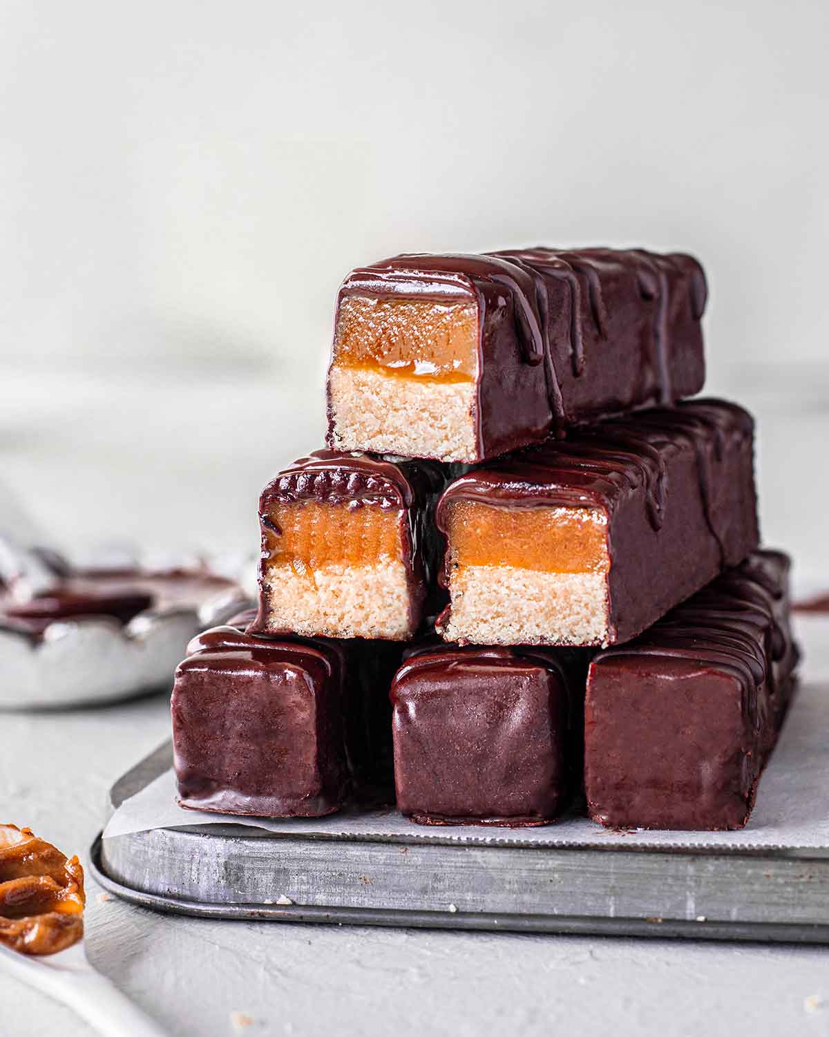 Chocolate caramel bars stacked on a silver tray.
