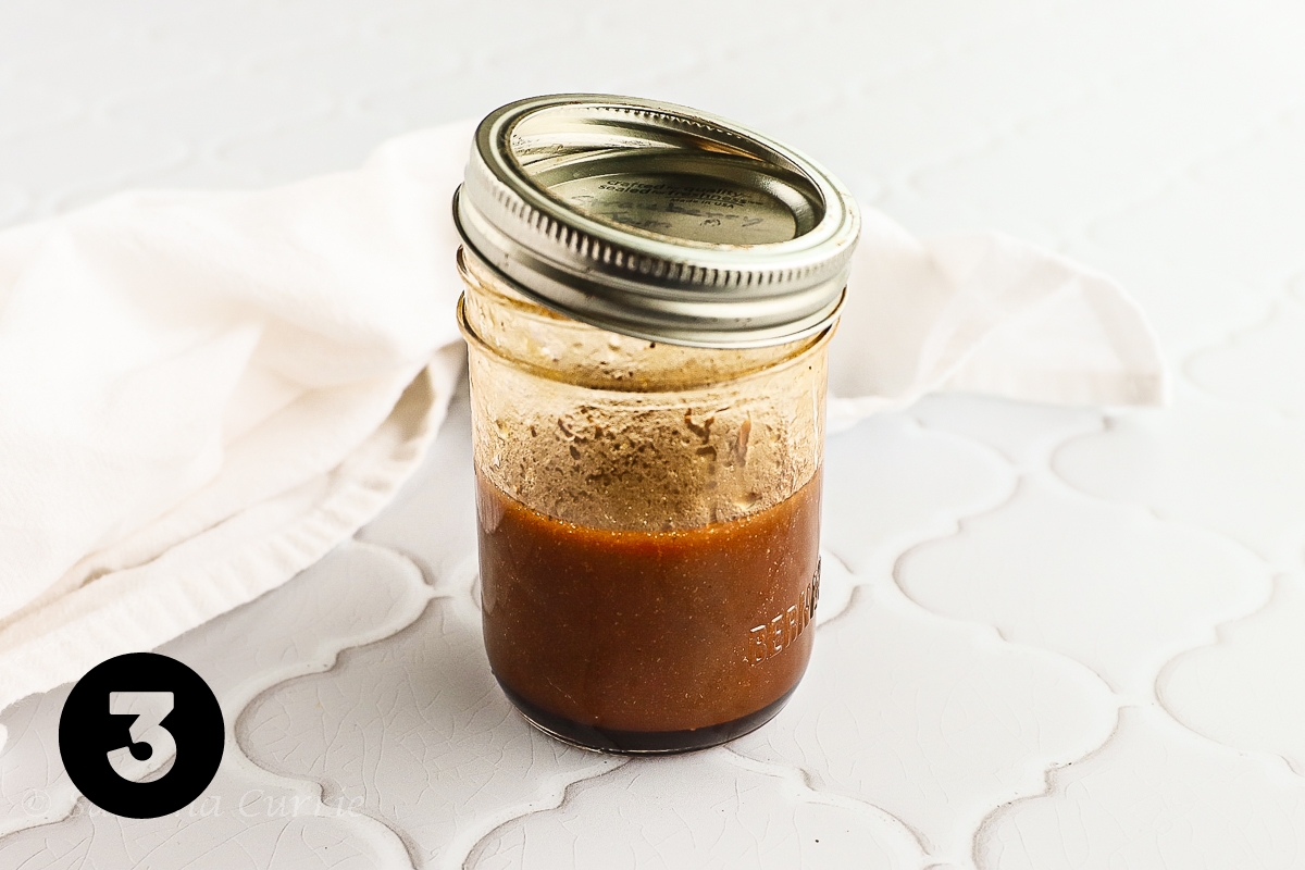 Reddish brown salad dressing in a small canning jar with a lid.