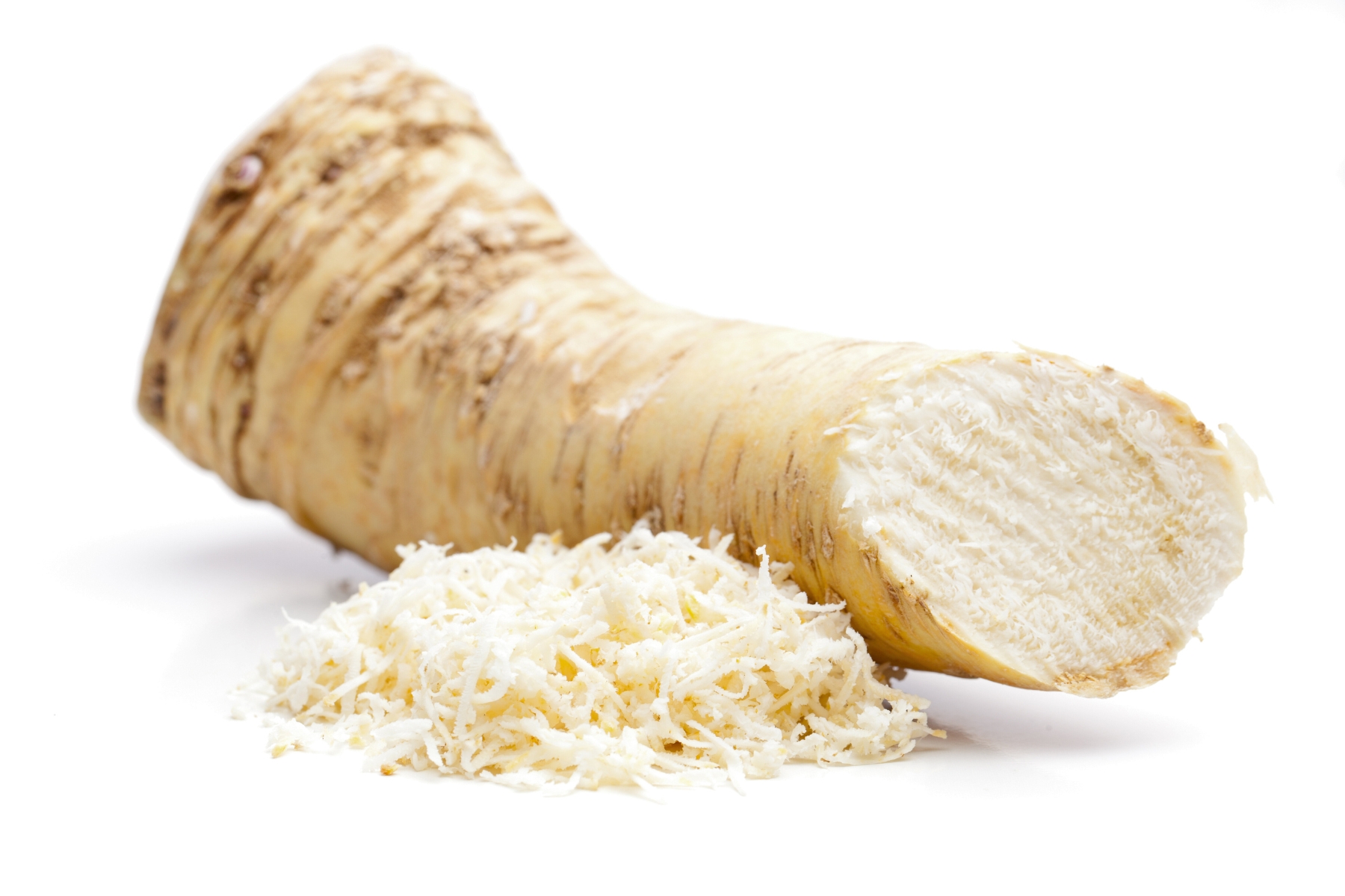 A chunk of fresh horseradish root with some grated finely beside. The outer root is pale tan colored and the grated root is white.