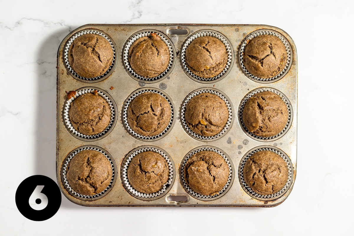 Muffins are baked and puffy dark golden brown and still in the baking tin.