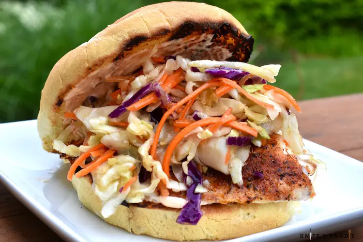 Burger bun filled with blackened cod and colorful coleslaw.