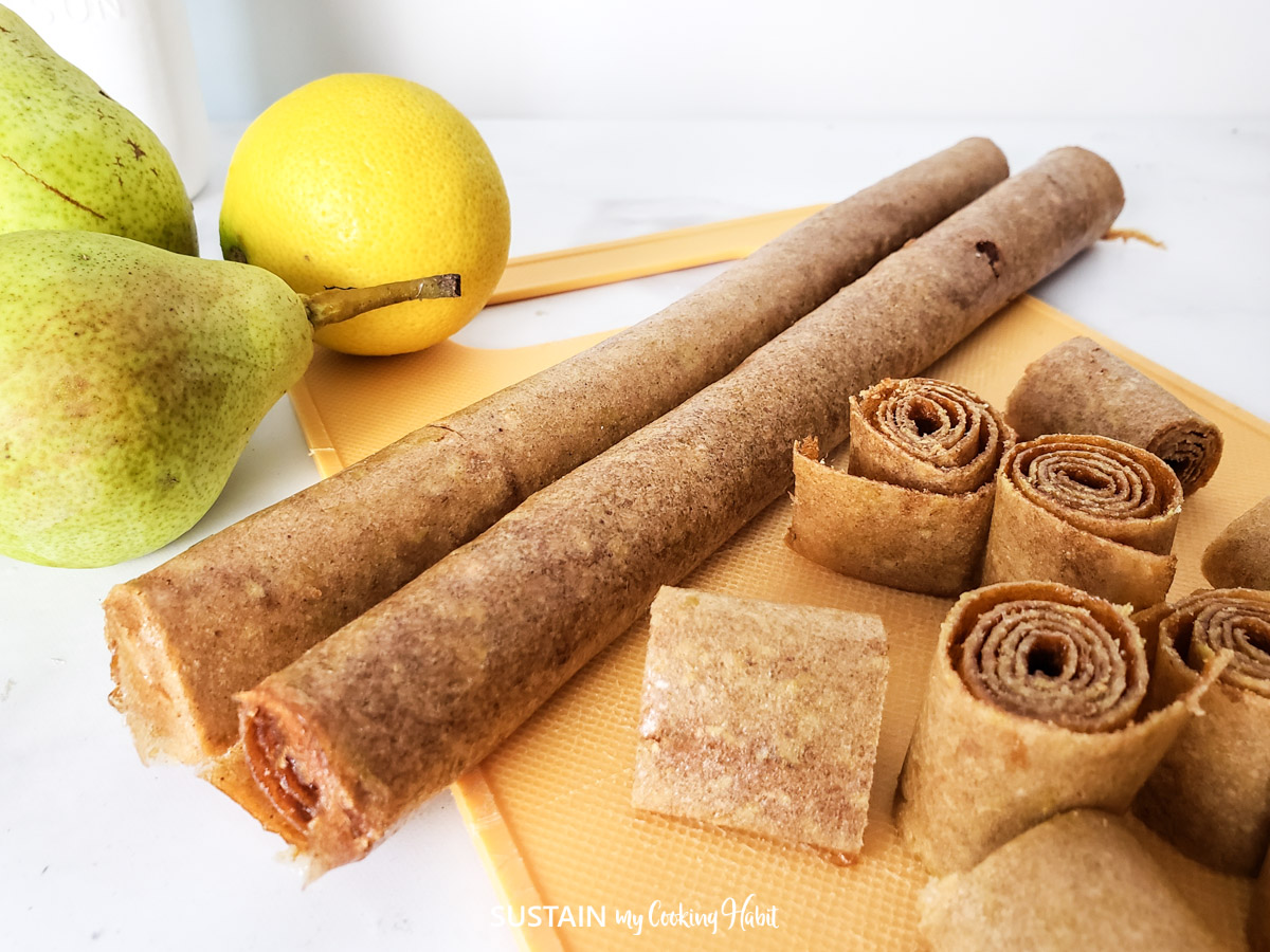 Pears beside rolled up light brown fruit leather.