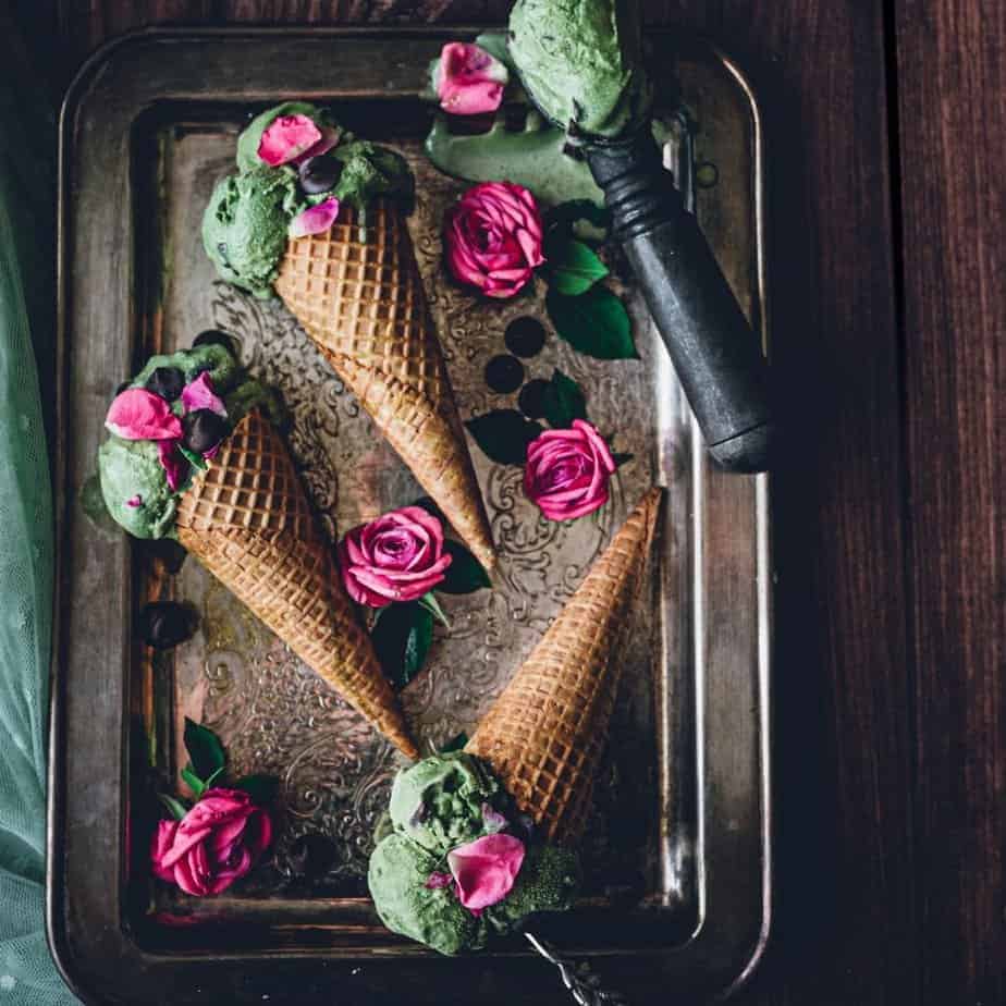3 waffle ice cream cones with fresh mint green ice cream surrounded by pink rose petals.