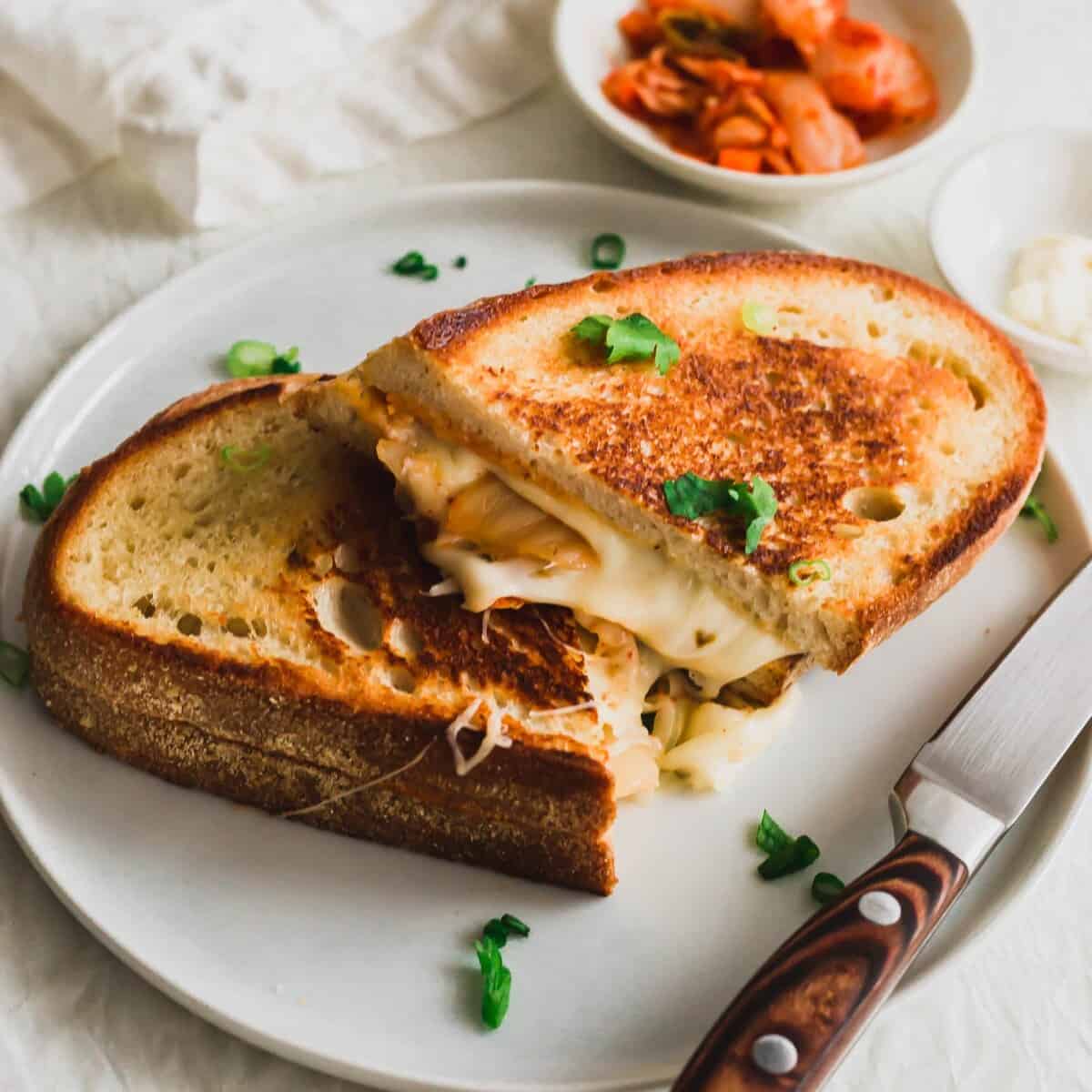 A grilled cheese sandwich with golden toasted white bread, cut in half with melted white cheese oozing out.