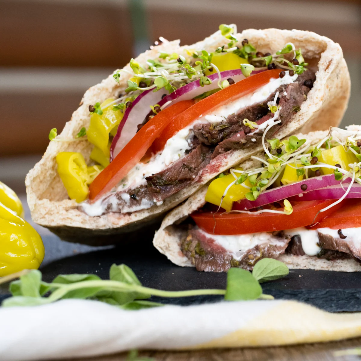 Two open pita pockets filled with pronghorn meat, lettuce, tomato and white tzatsiki sauce.