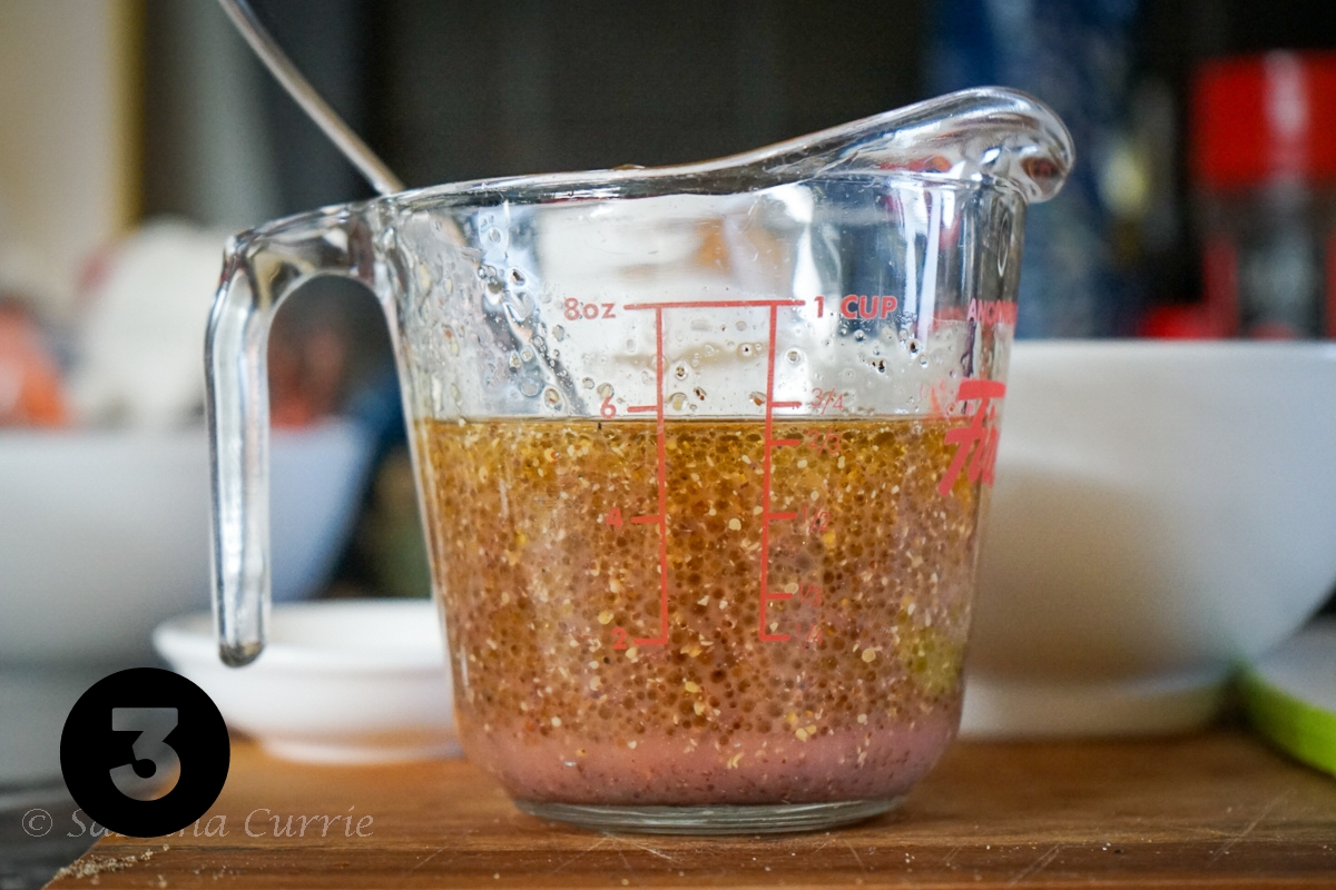 Clear glass measuring cup with emulsified vinaigrette.