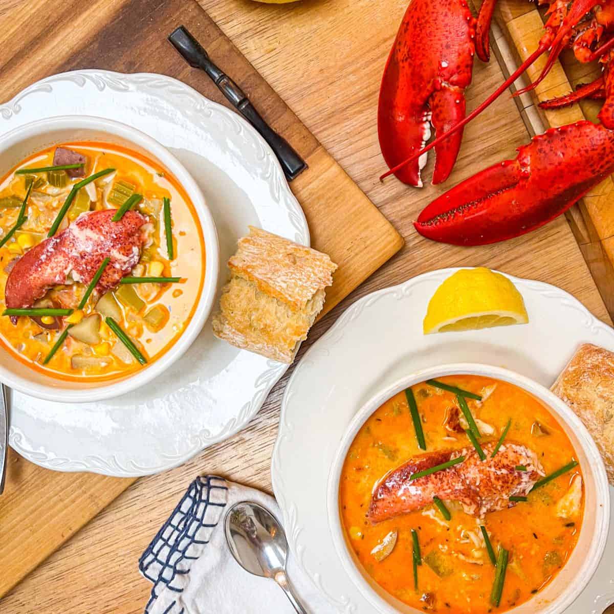 Two bowls of bright orange lobster soup with bright pink chunks of lobster claw meat on top.