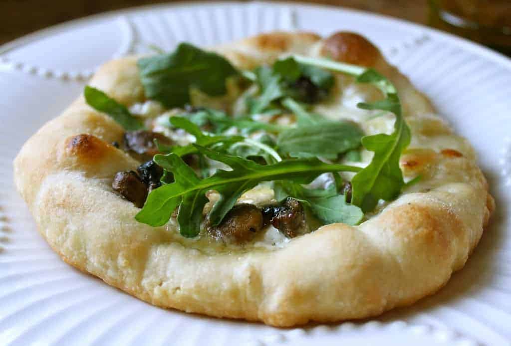 Small pizza topped with arugula and sliced truffles.