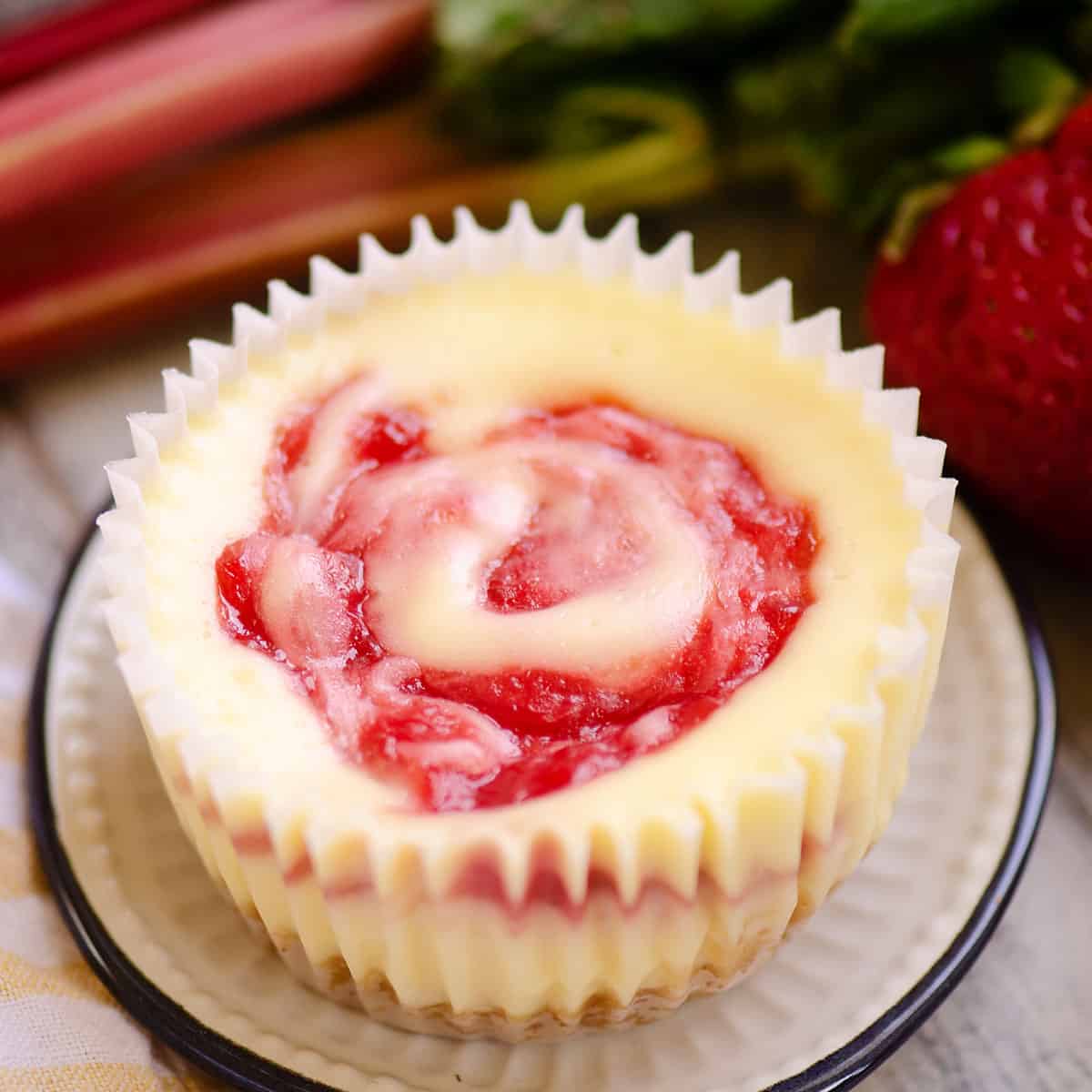 Small white cheesecake with pink swirls in the middle in paper cupcake liner.