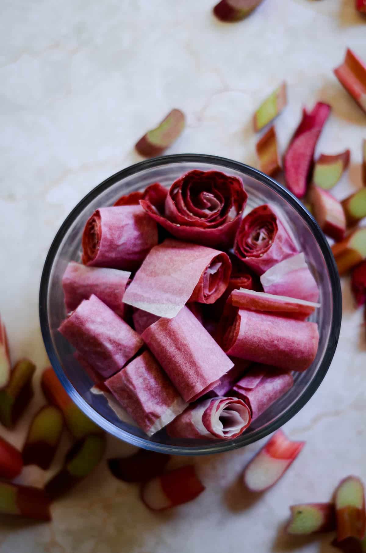 Dark pink-purple rolls of fruit leather in a clear bowl.