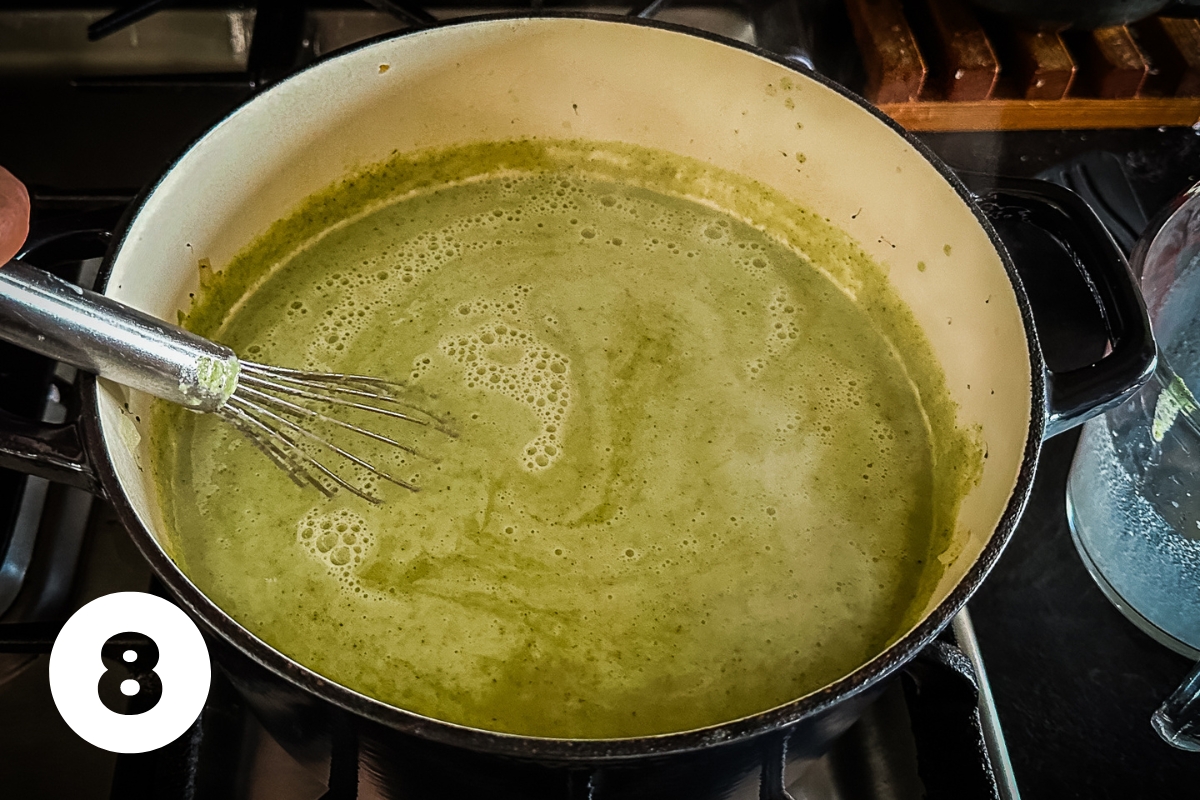 The cream mixture is stirred into the vegetable soup and you can see swirls of lighter green from the addition of the cream.