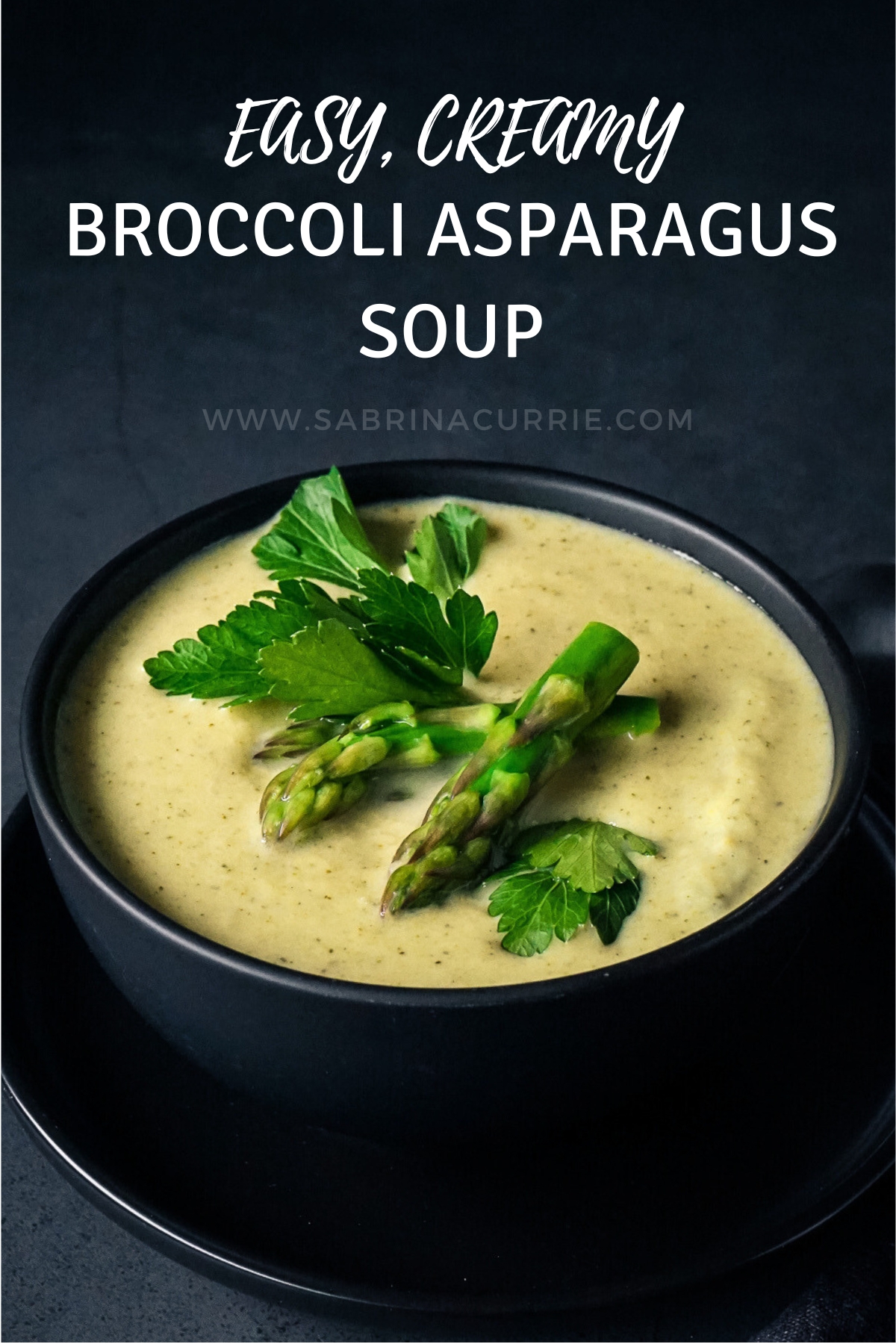 Black bowl of pale green-yellow soup topped with bright green asparagus tips.