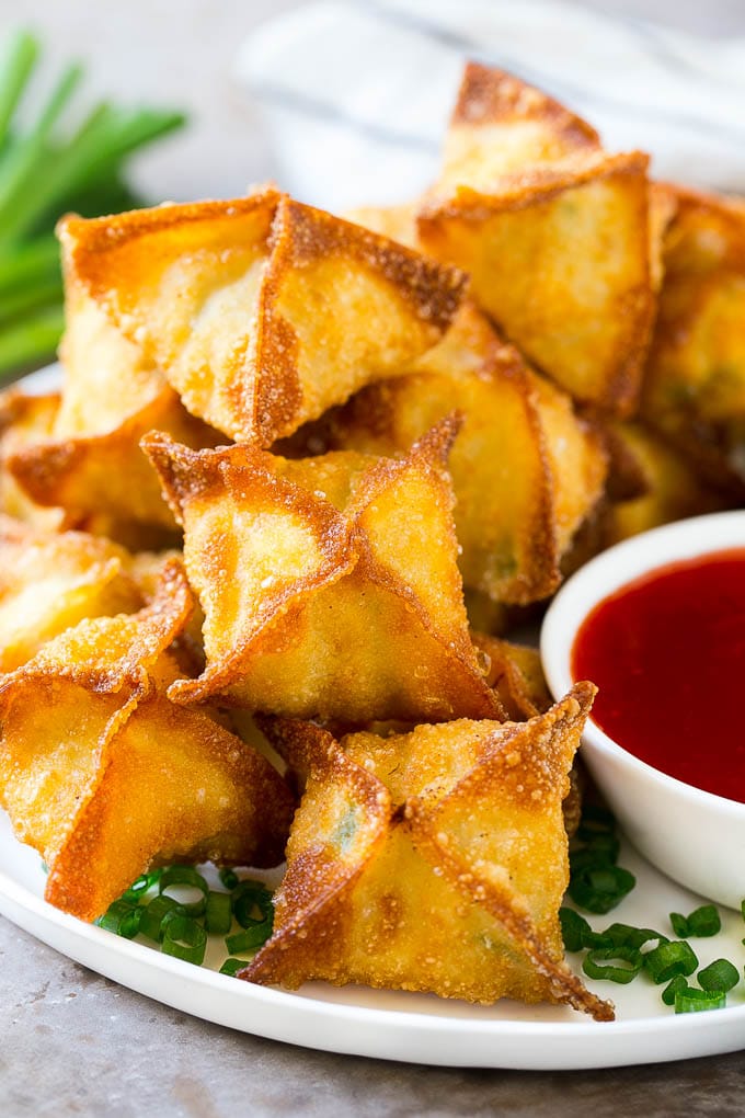 Crispy wonton wrapped parcels with a deep orange dipping sauce beside.