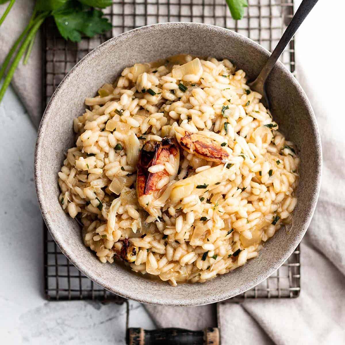 Risotto rice topped with crab leg meat in a grey frying pan.