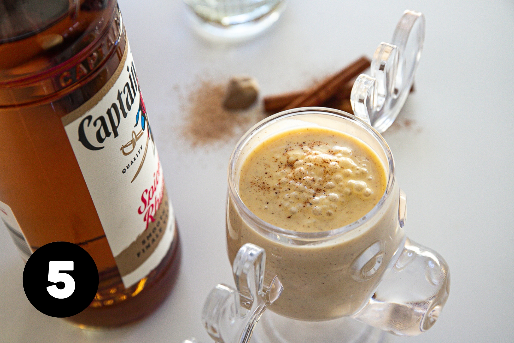 Frothy and bubbly eggnog in a clear glass moose mug, the same mug that's in the Christmas vacation movie.