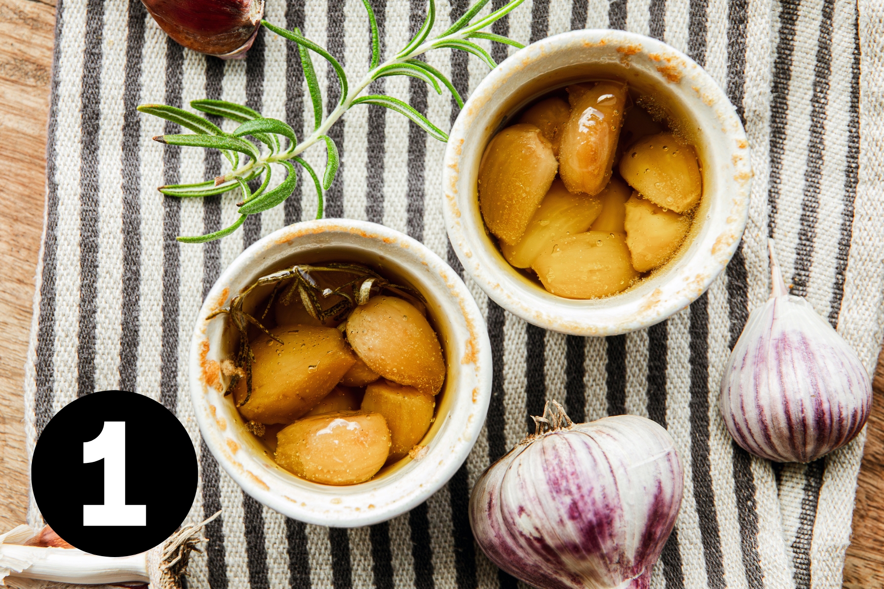 Two ramekins full of oil and light brown cloves of garlic.