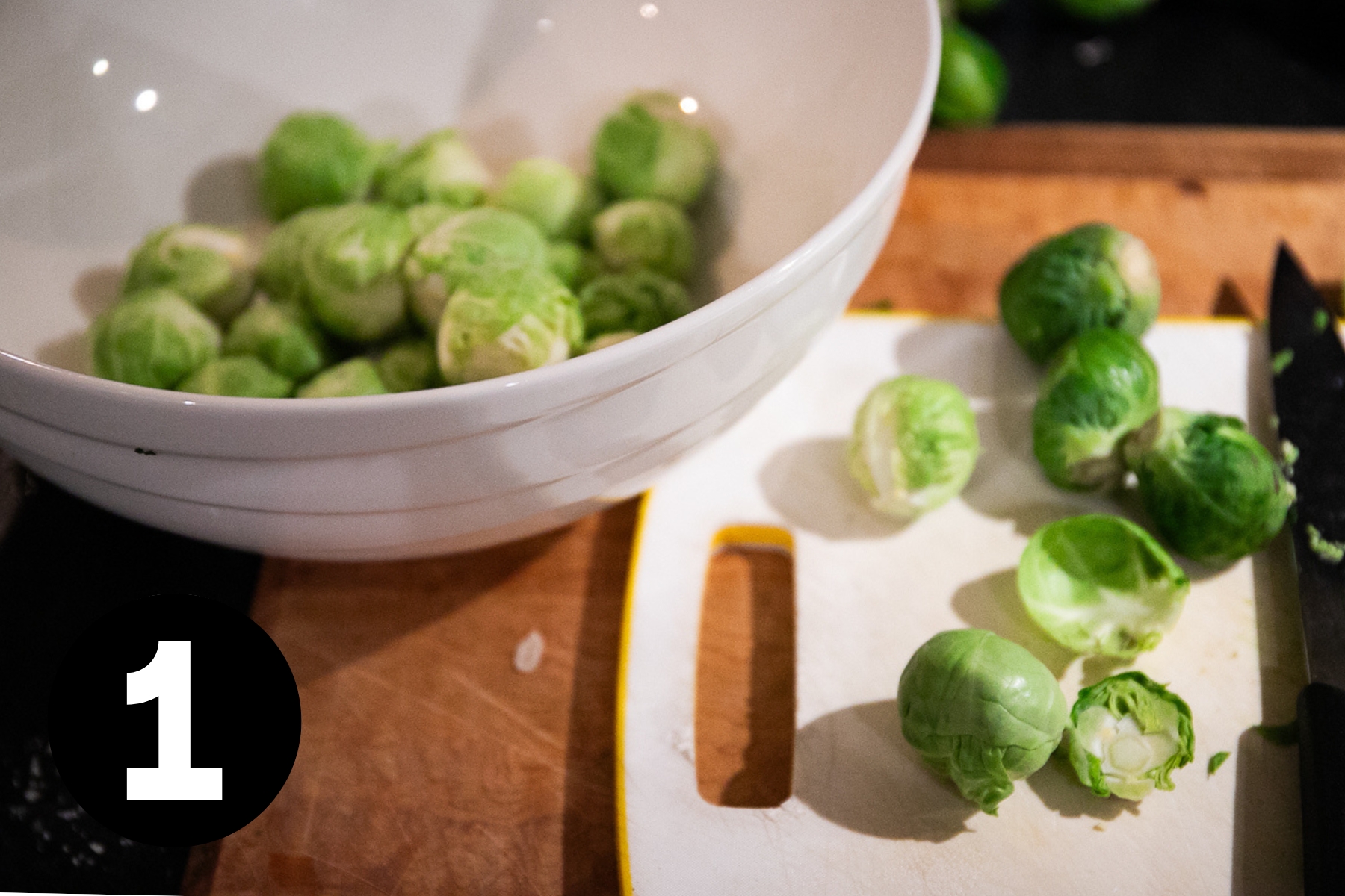 Brussel sprouts with dark leaves peeled off and sitting beside with a knife.