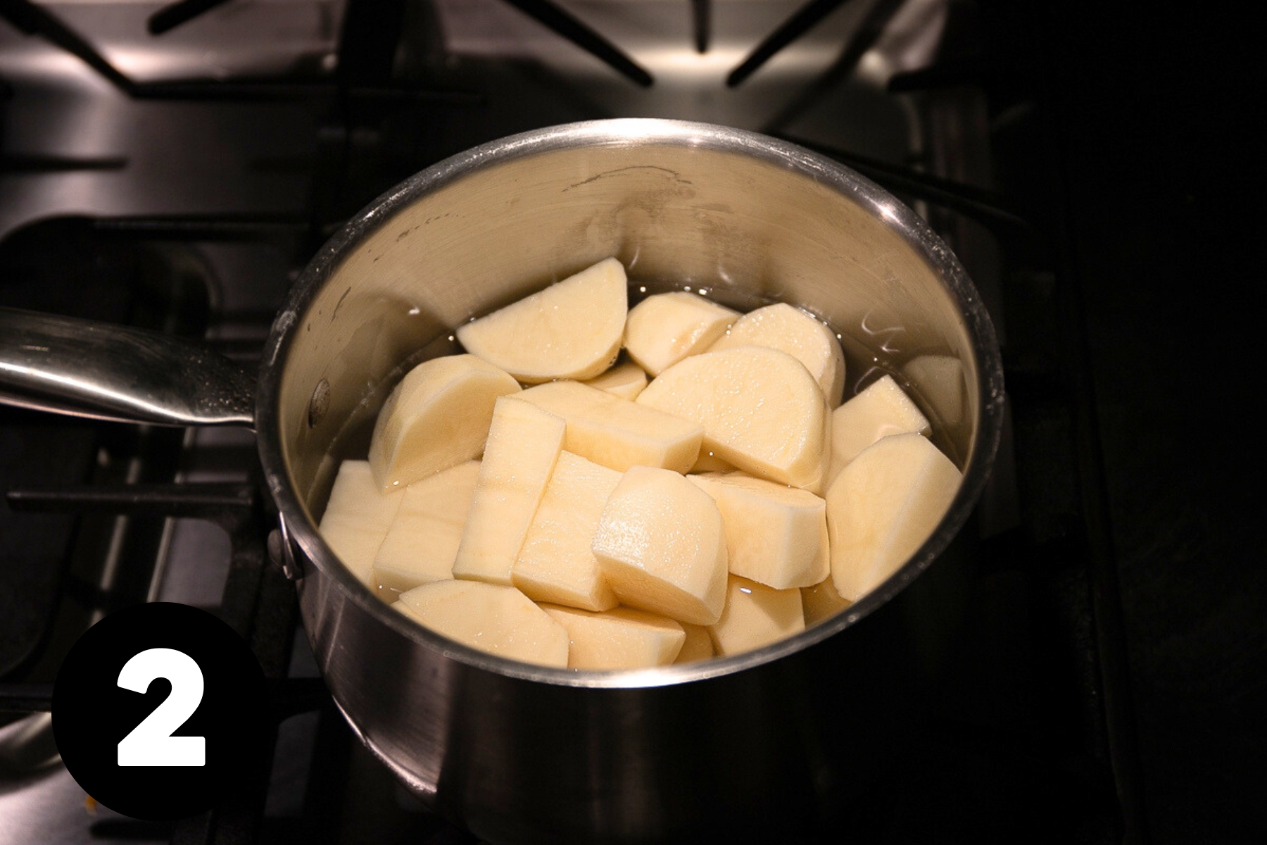 Peeled and cubed potatoes in a pot half full of water.