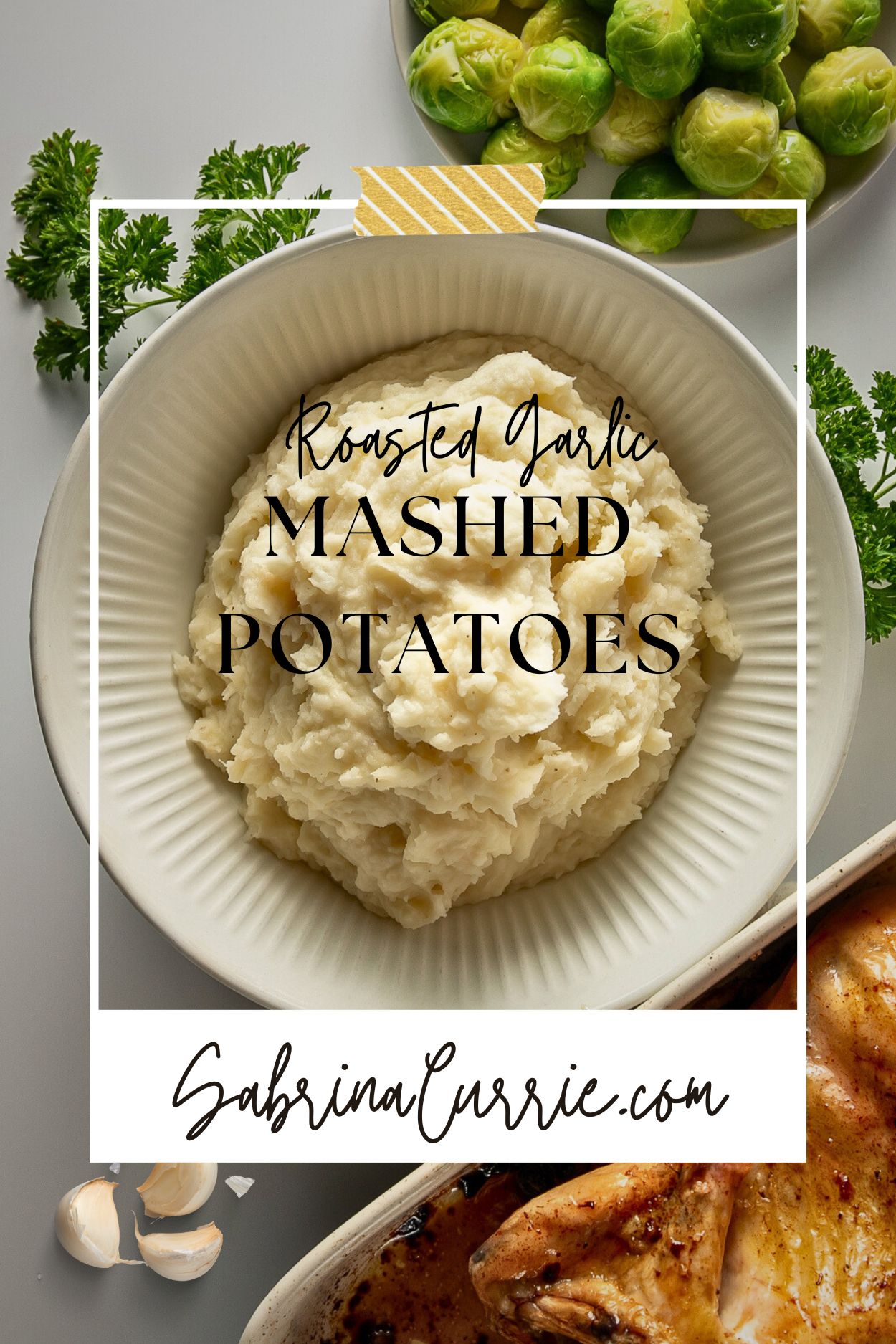 A bowl of mashed potatoes beside some Brussels sprouts, parsley, garlic cloves and a roast chicken.