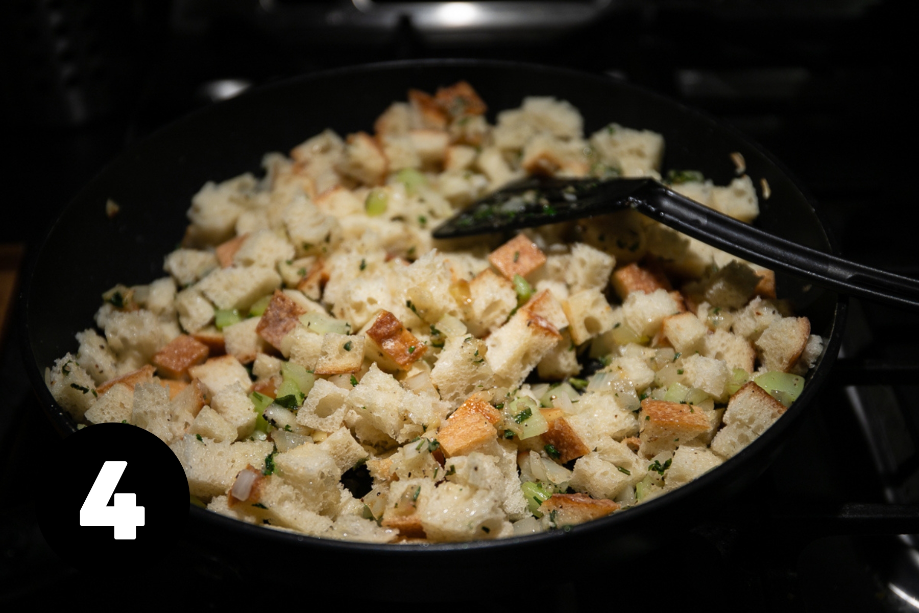 Bread cubes added to frying pan and mixed with the fried vegetables and herbs.