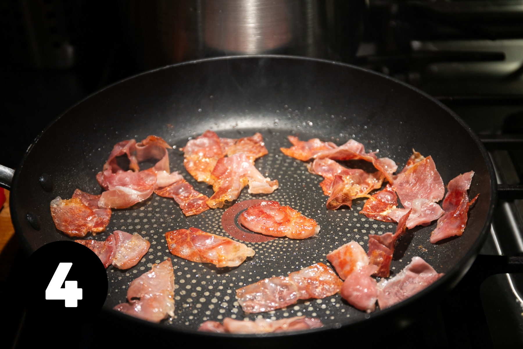 Pieces of crispy prosciutto in a large frying pan.