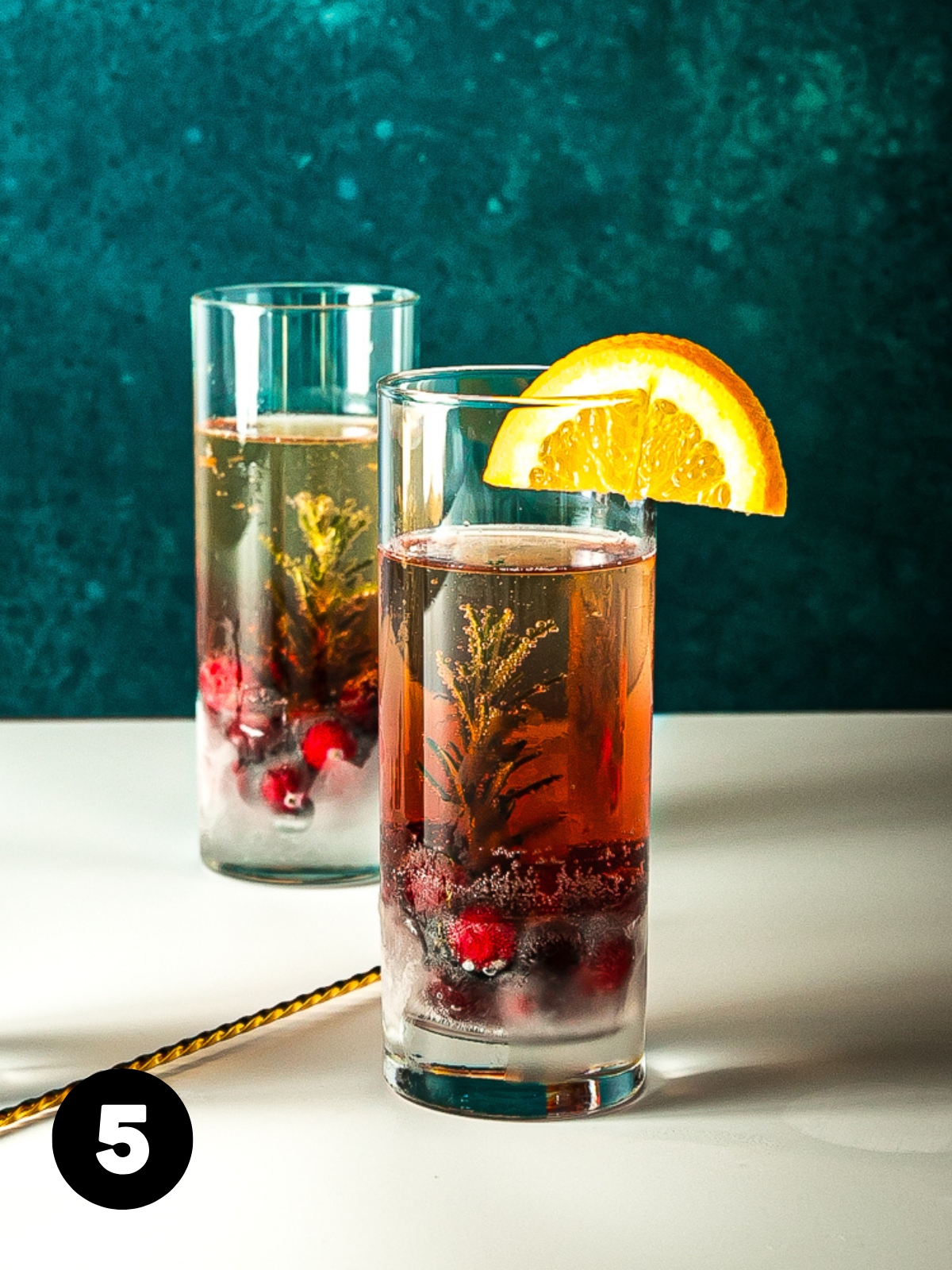 Finished drink with red on the bottom and fizzy golden liquid on top and a half orange wheel garnish.