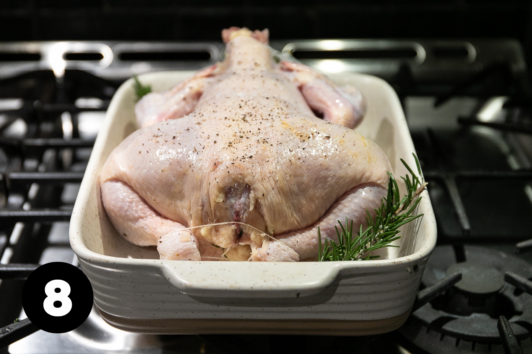 The chicken is upside down (breast side down) in the roasting pan.