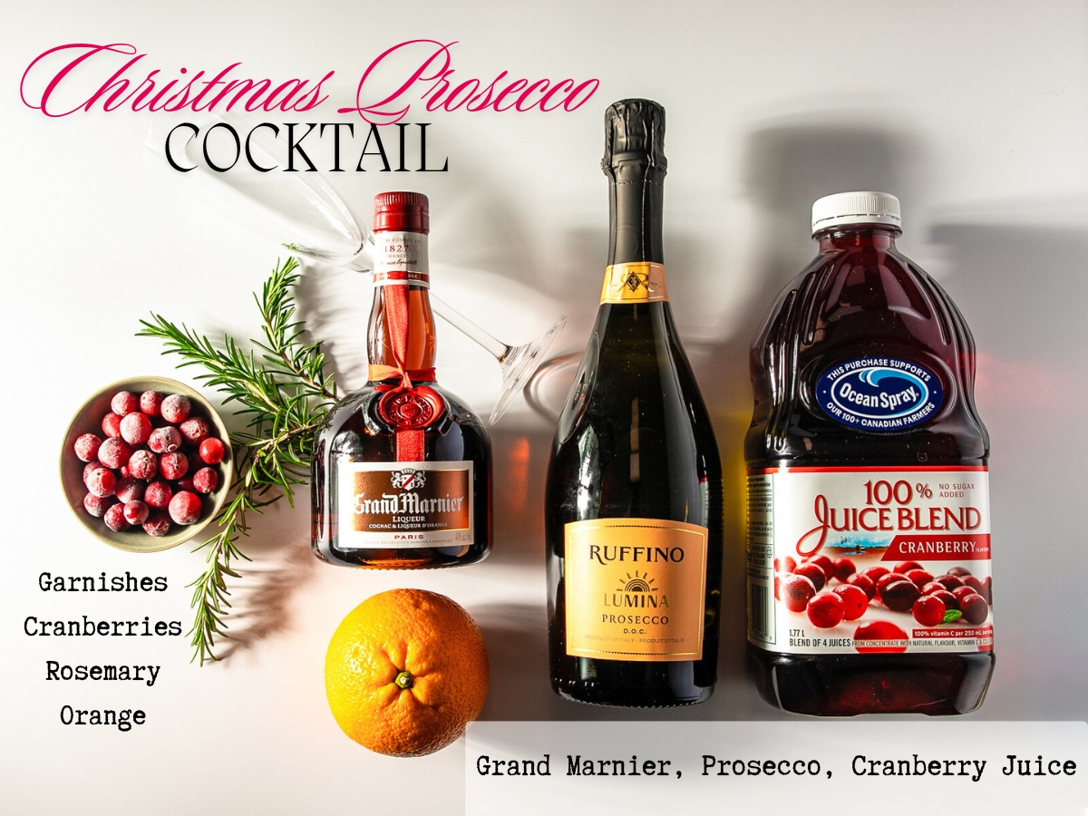 Bottles of prosecco, cranberry juice and Grand Marnier along with some rosemary sprigs, a bowl of cranberries and an orange.