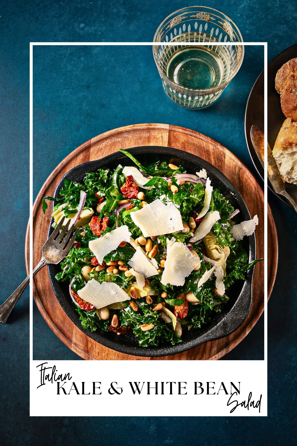 Bowl of kale salad topped with sundried tomatoes, artichokes, beans and parmesan.