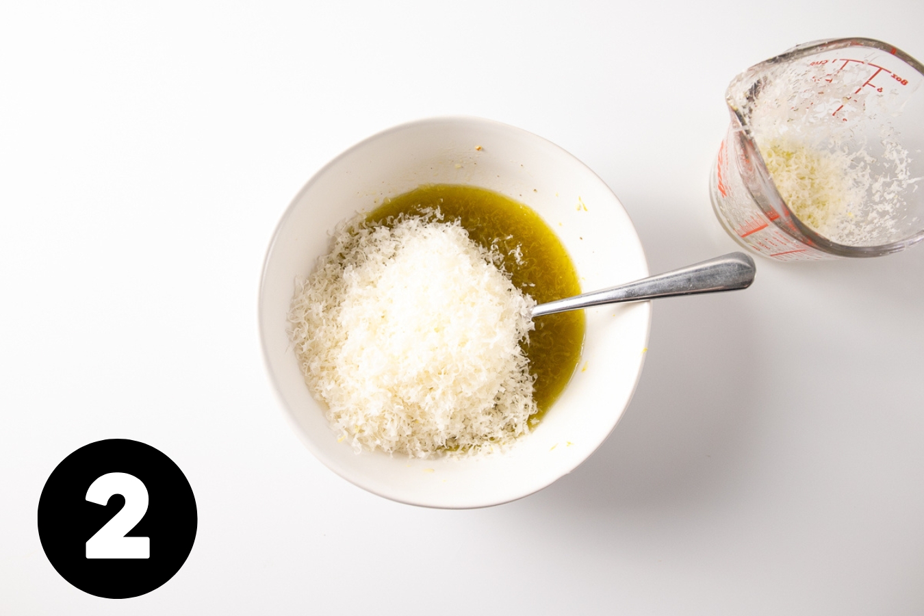 Bowl of dressing with a pile of finely grated parmesan on top.,