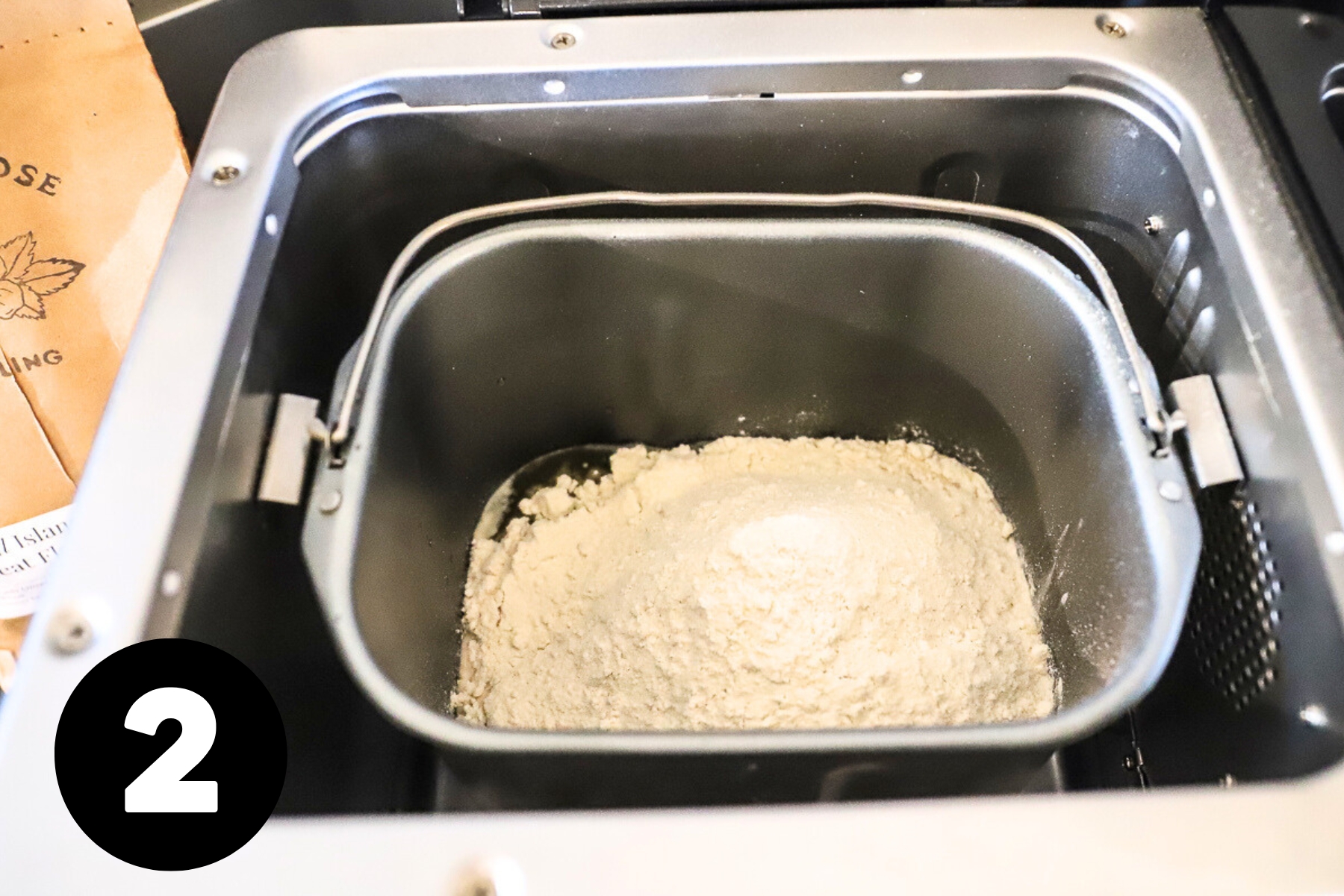 Flour heaped into the bowl of the bread machine.