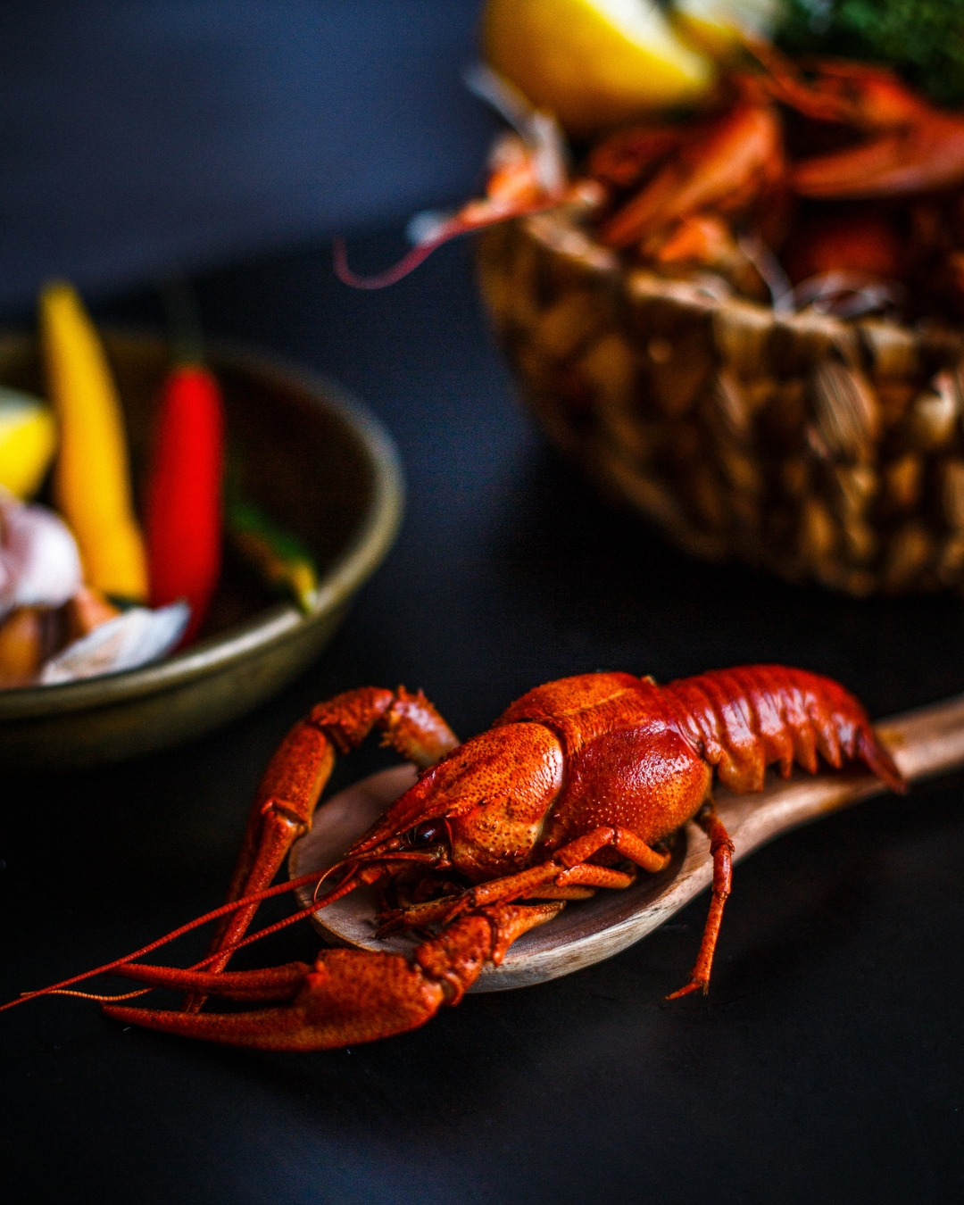 Cooked whole spiny lobster held on a wooden spoon.,