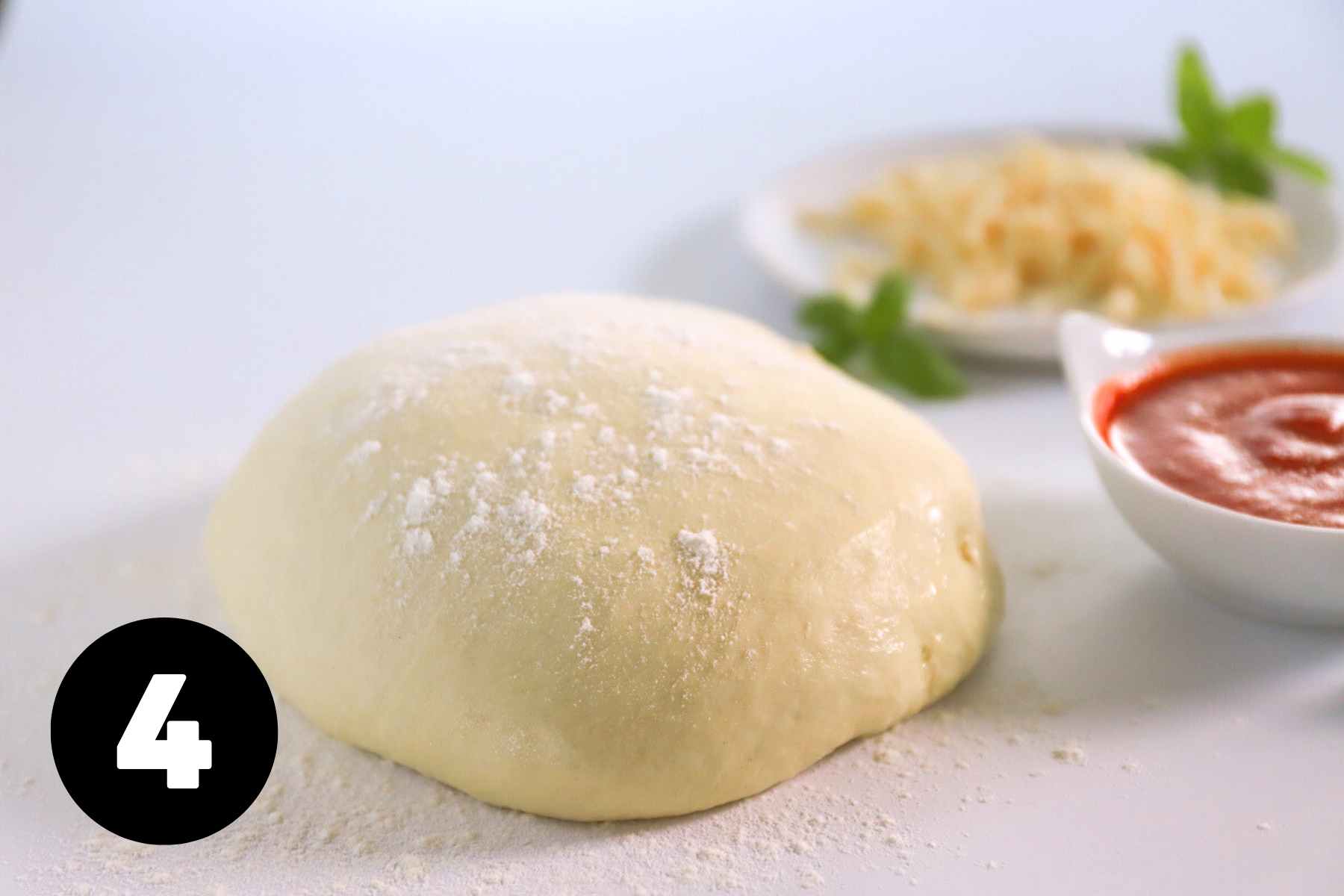 A ball of pizza dough on a countertop dusted with flour.