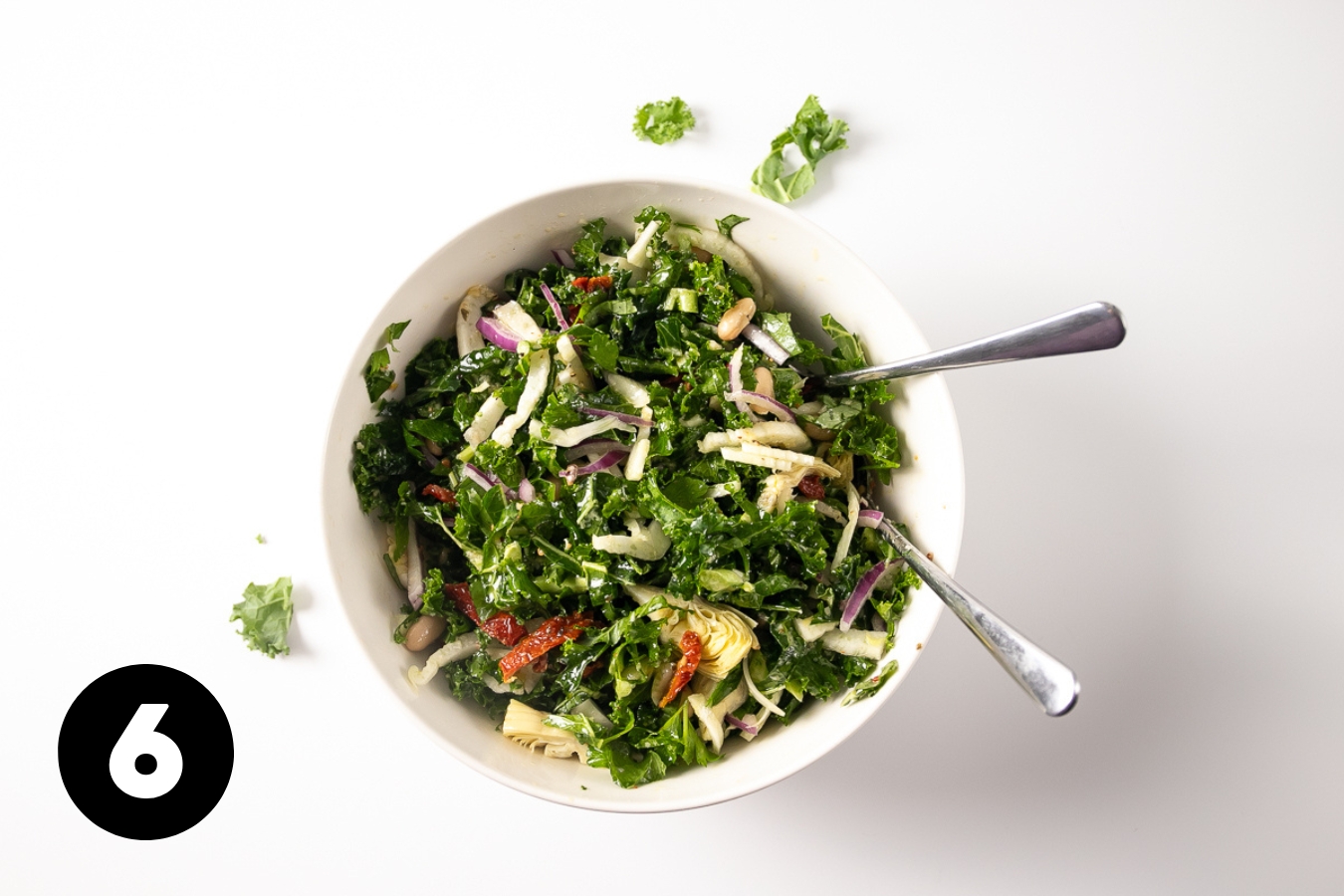 The finished, tossed salad in a large bowl with 2 spoons in it.