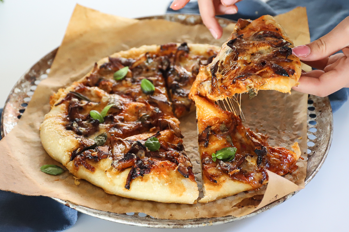 A bubbly browned mushroom pizza cut into wedges.