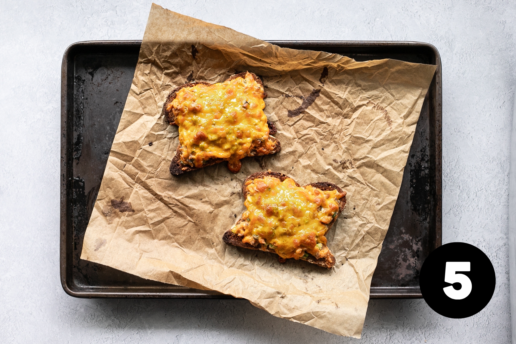 The broiled salmon melts sitting on the baking tray with bubbly cheese on the tops.