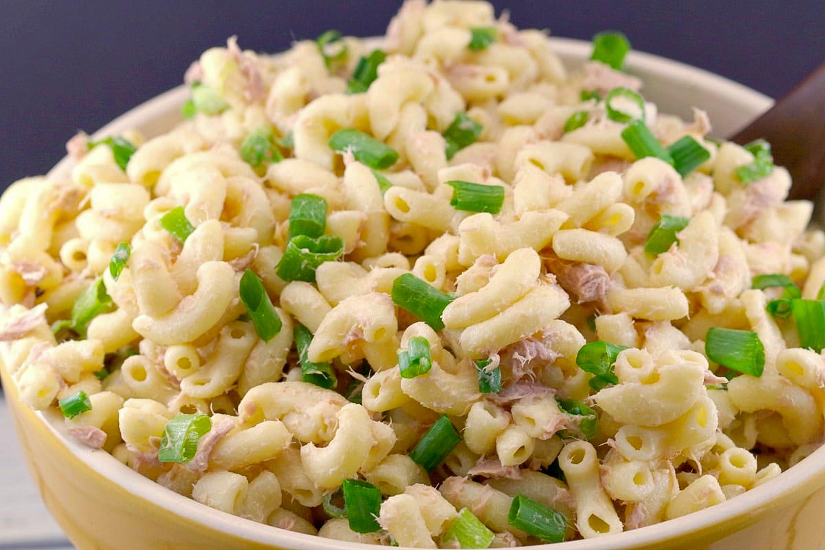 A bowl of macaroni noodles, chopped green onions and crumbled tuna fish salad.