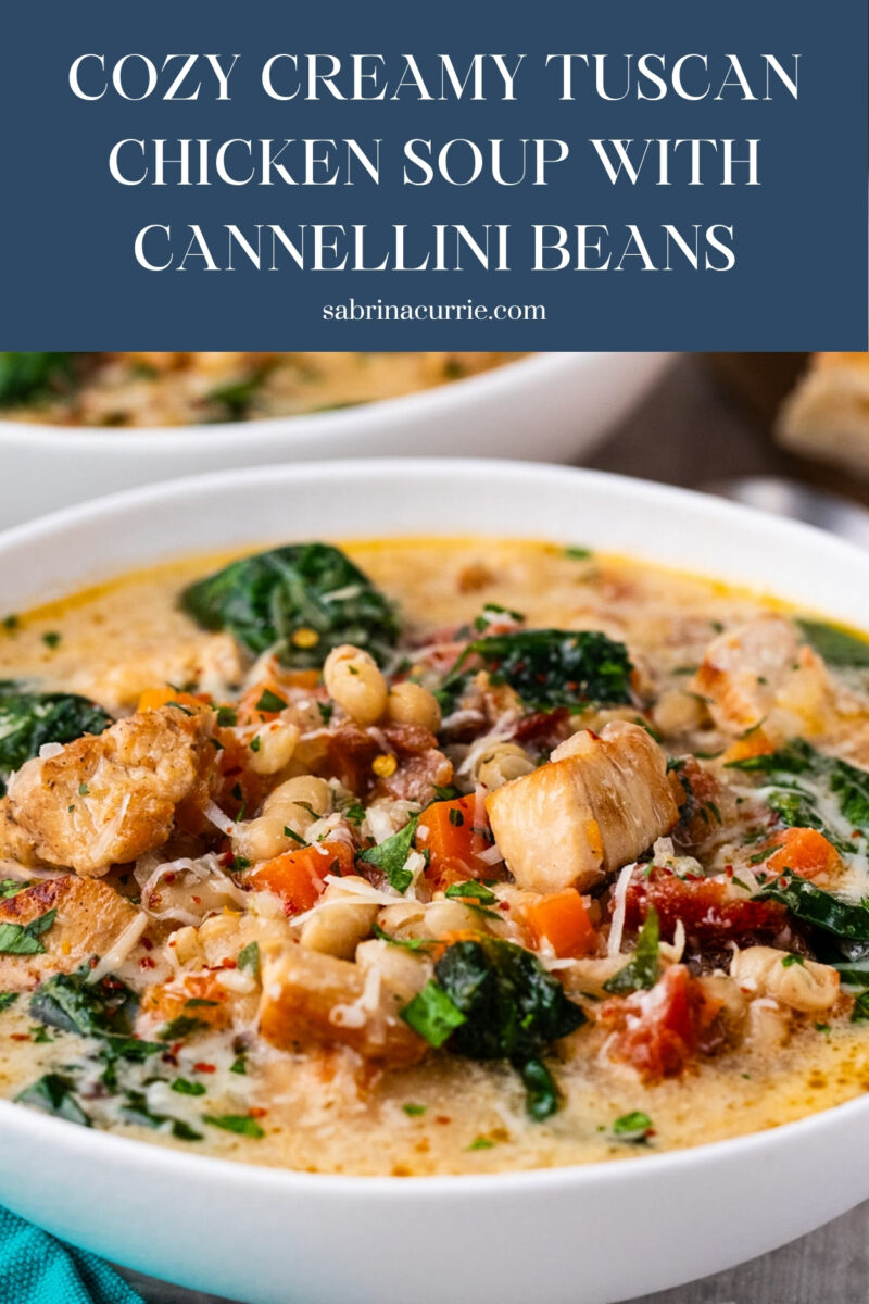 Bowl of chunky, creamy soup with spinach, beans, tomatoes and chicken.