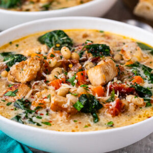 Creamy, chunky chicken and bean soup with spinach in a bowl topped with a little grated parmesan cheese.